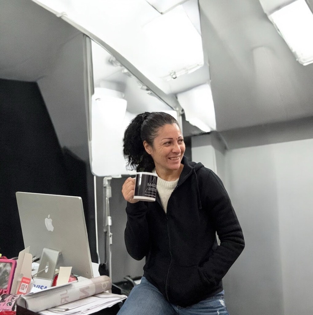 
Claudia Ottone sorride con una tazza in mano davanti al computer durante l’organizzazione di Medium Art Experience.